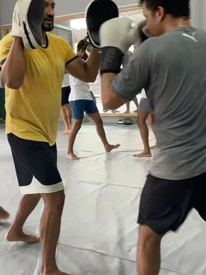 Close up on a partner drill, with one member holding pads while the other throws a punch.