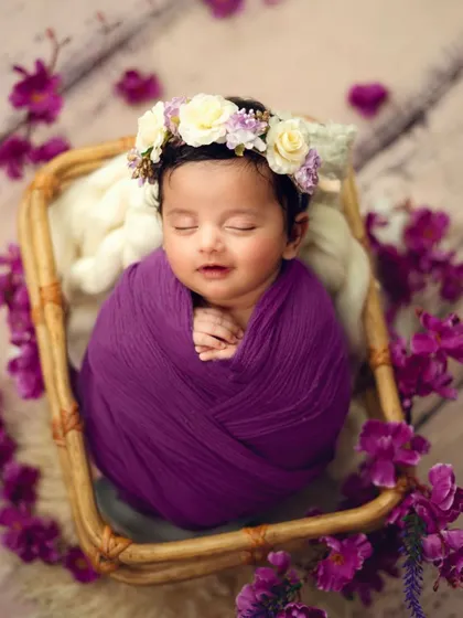 A floral crown and a deep purple wrap create a dreamy, fairytale look. I love how this baby is smiling in her sleep, a truly magical moment to capture.
