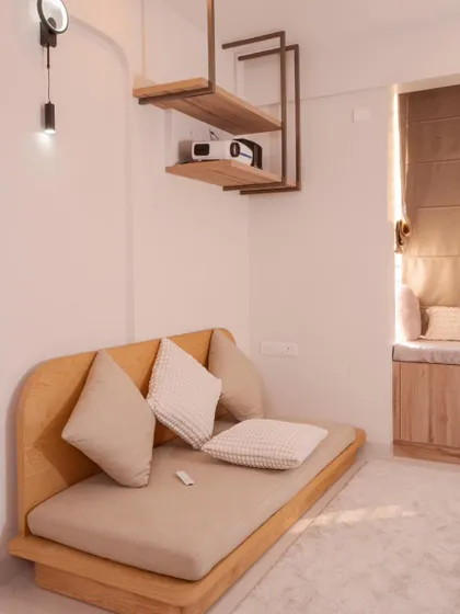 This entertainment room at Mana Capitol features a low-seater sofa and unique ceiling-hung shelves, perfect for a projector setup in a minimalist style.