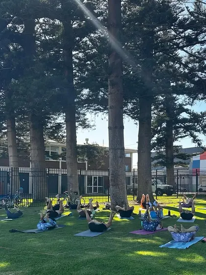 Students engaging their core with a leg-lifting exercise during our outdoor community class. This builds strength and stability.