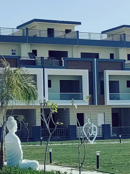 The landscaped central park of the Kanpur row housing project. The serene setting, complete with a Buddha statue, provides a peaceful recreational space for residents, framed by the contemporary architecture of the homes.