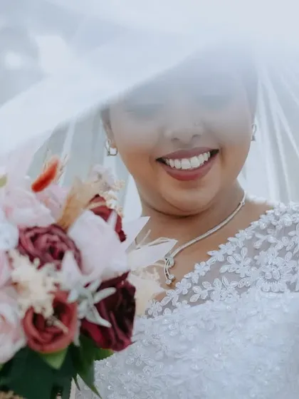 A bright and airy portrait of the bride, with her smile lighting up the frame. The focus is entirely on her happiness and the delicate details of her dress.