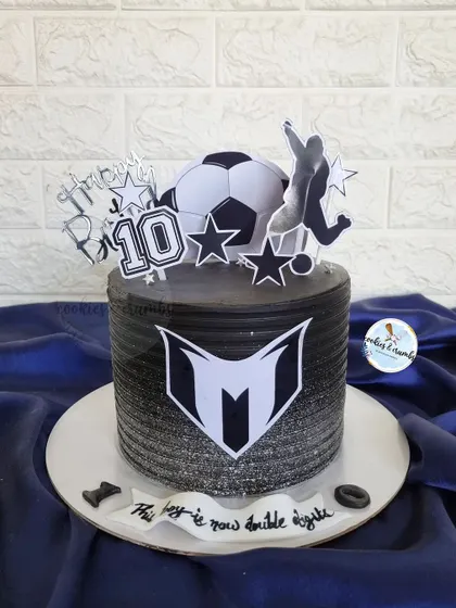 A sleek and modern football-themed cake. The black and silver spray effect, custom logo, and soccer toppers make this a cool choice for a 10th birthday.