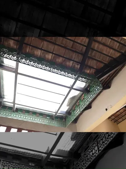 The skylight in the Padmaja Rao Residence is framed with ornate green metalwork, adding a decorative flourish to this functional element and enhancing the traditional aesthetic.