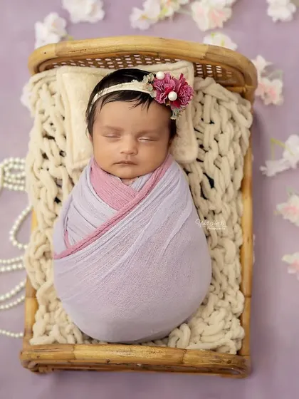 An overhead view of the lavender-themed setup, with the baby girl looking like a tiny sleeping beauty surrounded by pearls and flowers.