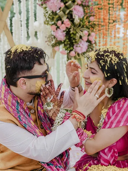 The Haldi ceremony is a burst of joy, and we capture every bit of that playful energy. This shot of the couple being showered with flowers shows our love for vibrant, candid moments that are full of life and laughter.