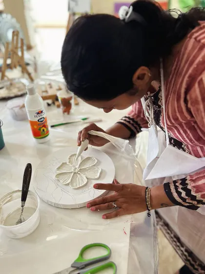 Using a cone to apply texture paste to create raised floral designs.