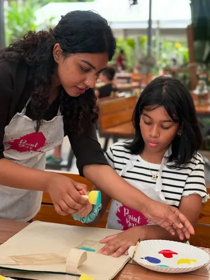 An instructor helping a young artist with her stencil tote bag painting. We're always on hand to offer guidance and support.