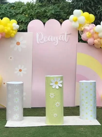 A sweet daisy-themed party with modern, arched backdrops. The pastel yellow and pink balloon garlands are shaped into flowers, adding a charming touch.