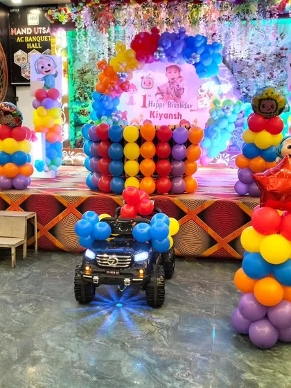 A fun shot of the Cocomelon party setup with a decorated toy car in the foreground. The headlights are on, adding a playful touch to the overall grand decoration.