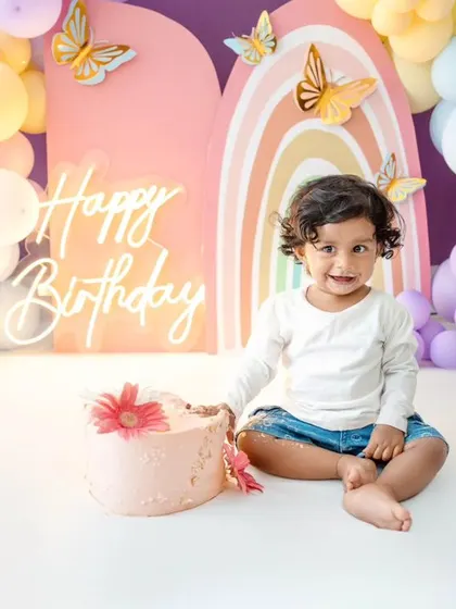 A sweet portrait of the birthday girl before the cake smash. Her adorable pink dress matches the pastel theme perfectly.