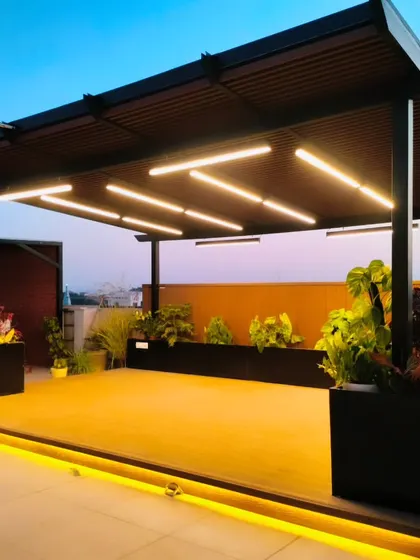 The completed pergola at our Palam Vihar project, seen at sunset. The raised deck is illuminated with strip lighting, and the structure is surrounded by planters.