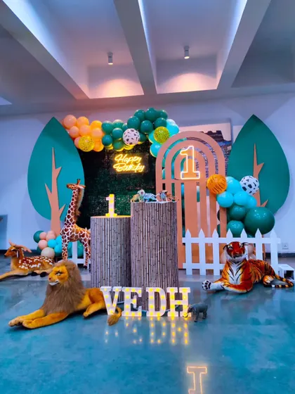 A classic jungle theme birthday party. This setup features large leaf-shaped backdrops, bamboo-style plinths, and friendly animal props, perfect for a "Wild One" celebration.