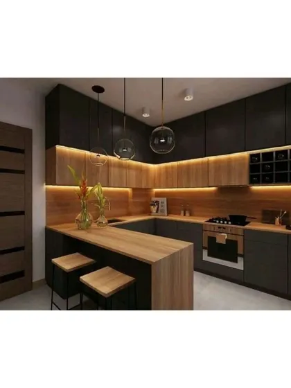 This U-shaped kitchen features a breakfast counter and a mix of dark and wood-finish cabinets. The pendant lights and under-cabinet lighting create a warm and inviting ambiance.