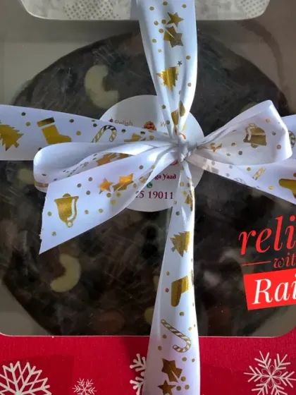 A beautifully packaged Christmas Plum Cake, ready for gifting. This rich, boozy fruitcake is loaded with rum-soaked dried fruits and nuts, and blended with authentic spices for a truly festive flavor.