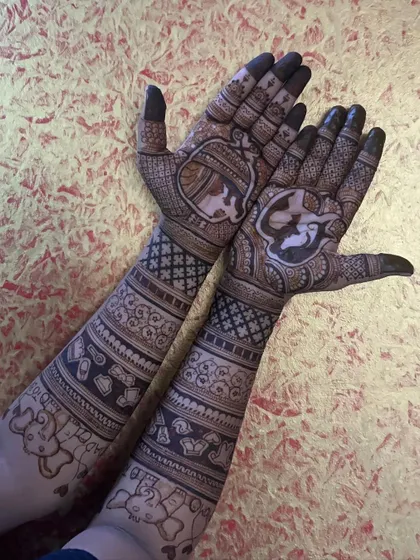 A full view of this intricate baby shower mehendi, featuring a mother and baby in the palm and various baby-related items along the arms.