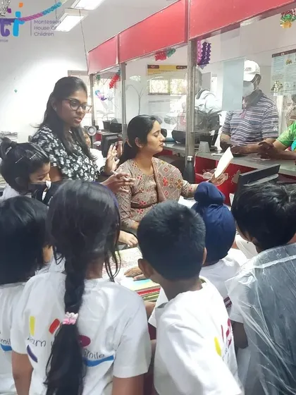 Children interact with a postal worker at the post office counter. This field trip taught them about the journey of a letter and the workings of our postal system.