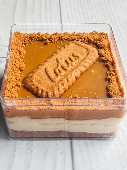 A side profile of the Lotus Biscoff Cheesecake Tub. You can see the distinct layers of the biscuit base, creamy cheesecake filling, and the smooth Biscoff spread on top.