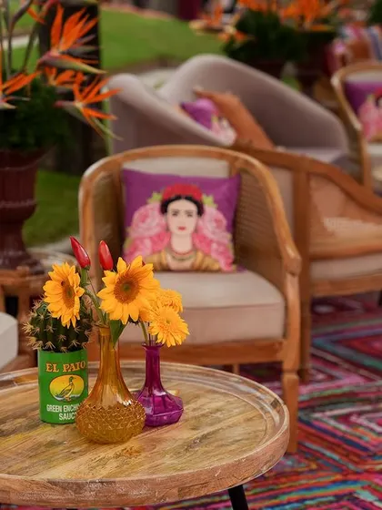 A close-up of a tabletop arrangement, featuring a cactus, sunflowers, and colorful vases.