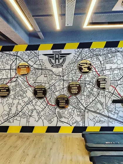 A custom doodle map mural for Roadies Gym, highlighting different locations. This unique piece is bordered by a yellow and black caution stripe, fitting the industrial, rugged theme of the gym.