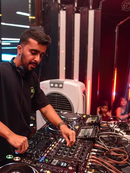 A shot of me at the decks, with the club's architecture framing the scene. I'm focused on delivering the best experience possible.