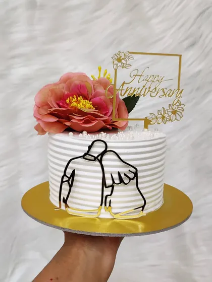 An anniversary cake with a modern touch. The striped buttercream is decorated with a couple's silhouette and a fresh flower for a romantic finish.