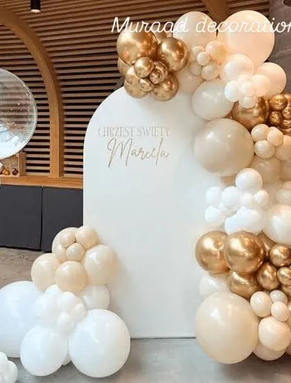 A classy and neutral-toned balloon decoration. The white arched backdrop is framed by a beautiful garland of white, cream, and chrome gold balloons, perfect for a baptism, naming ceremony, or elegant birthday.