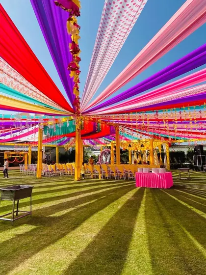A wide-angle shot of this large-scale Haldi setup, with a vibrant canopy of multi-colored drapes covering the entire guest seating area.