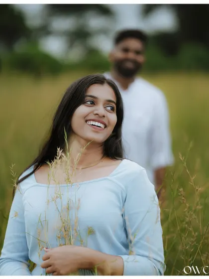 A beautiful portrait of the bride-to-be in a field, with her partner in the background, creating a sense of depth and story.