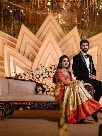 A wide shot of the couple seated on their reception stage, capturing the full splendor of the decor from a distance.