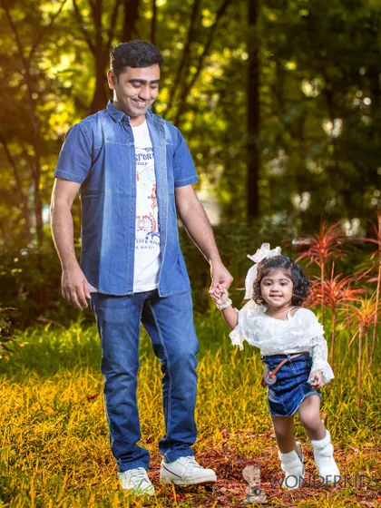A father and daughter walk hand-in-hand through a sunlit field. This is a classic, heartwarming portrait that captures a precious father-daughter moment.