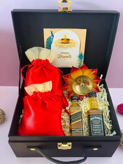 This hamper is ready for a celebration, containing two miniature whiskeys, dry fruits in potlis, and a brass diya, making it a complete Diwali package.