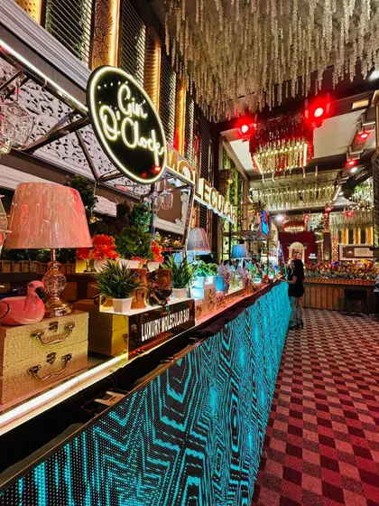 A full view of our expansive, multi-station bar with a vibrant, animated LED facade. This setup includes dedicated areas for different spirits, like the 'Gin O'Clock' station, ensuring a dynamic and engaging experience for all guests.