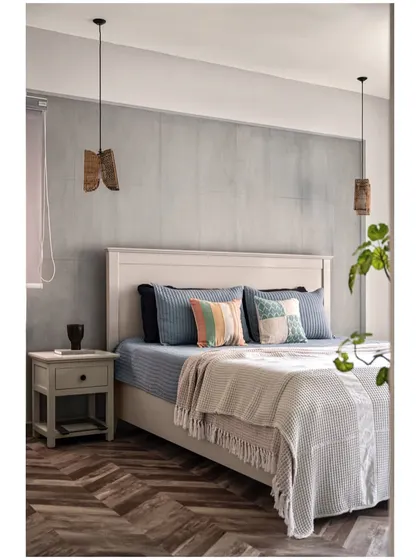 This bedroom from our "Between Shades of Grey" project features a concrete-finish accent wall, a herringbone wood floor, and hanging pendant lights for a modern, textural look.
