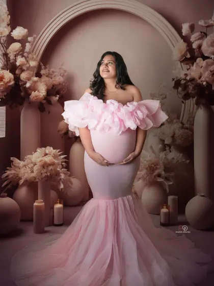 This mom-to-be is absolutely glowing in a pink mermaid-style gown with dramatic ruffles. The neutral, floral-adorned studio set lets her and the dress be the stars of the photo.