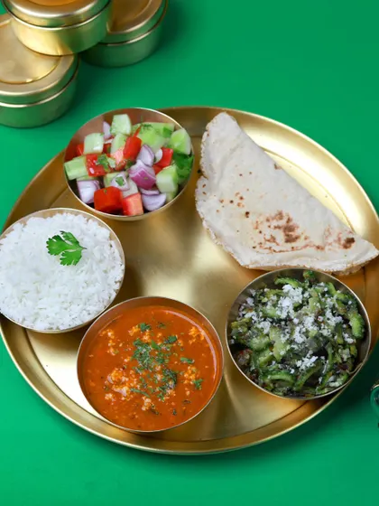 You have enough on your plate, let me handle what's in your tiffin. A beautiful meal of paneer bhurji, bitter gourd sabzi, rice, roti, and salad.