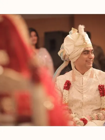 The groom's happy glance towards his bride. This candid moment, with the bride softly blurred in the foreground, tells a story of love and admiration from his point of view.