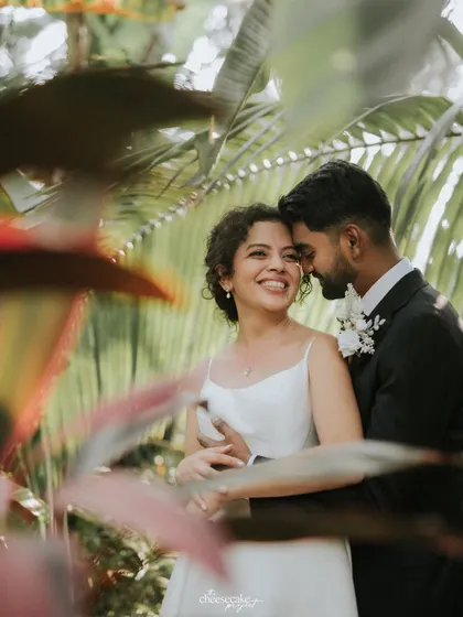 A beautiful, happy moment between the bride and groom, surrounded by greenery.