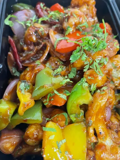 This is my Gobhi Manchurian, packed and ready to go. You can see the crispy cauliflower florets coated in a tangy sauce with colourful bell peppers and onions, garnished with fresh coriander.