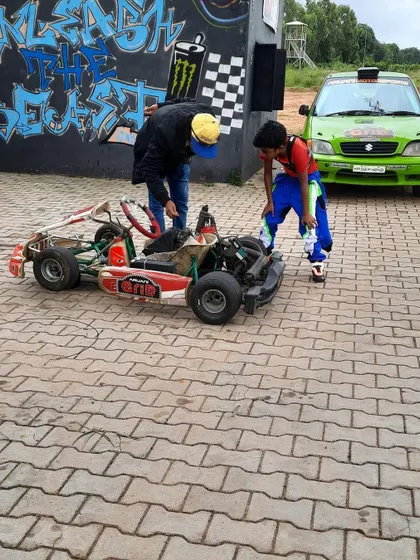 It's a team effort. A young driver gets help from his coach and mechanic to understand the kart's mechanics, learning about the machine he'll be piloting.