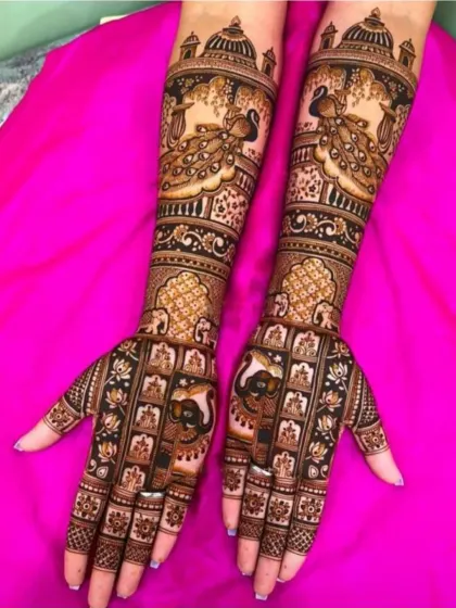 A royal Rajasthani bridal design featuring palace architecture on the arms and intricate peacock motifs. The use of negative space makes the detailed patterns stand out beautifully.