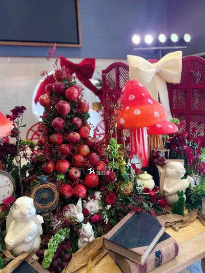 Another angle of the detailed tablescape, showing the mix of textures with apples, flowers, books, and character figurines.
