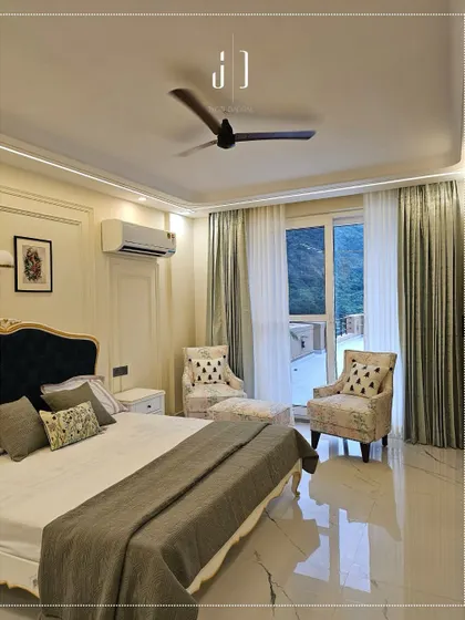 A bedroom at our "Aloha on the Ganges" project, featuring a classic bed design with a view of the outdoors. The floral-patterned chairs add a touch of charm and comfort.