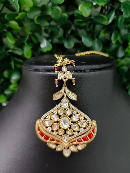 A unique maang tikka with a fan-like design in kundan and red enamel. This piece is for the bride who wants something truly different.