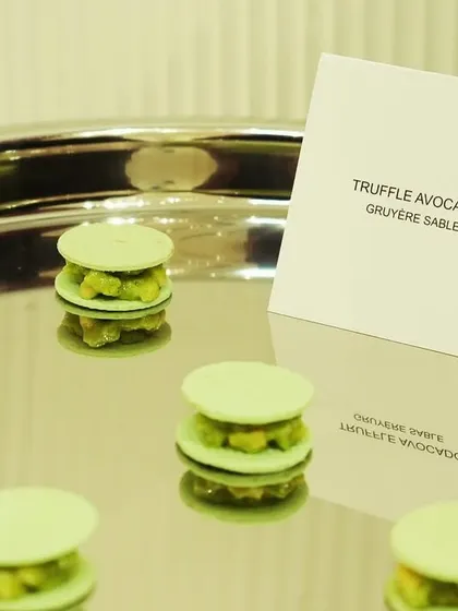 Savory truffle avocado macarons in a pale green, created for the Versace event. This dish showcases our ability to use color matching to visually integrate the menu with the brand's aesthetic.