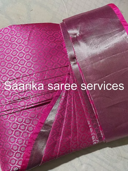 A bright pink saree with a silver border, pleated to create a stunning look. It's now ready for a party.