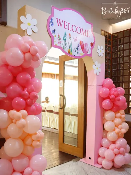 A welcoming entrance to a fairy-themed party, featuring a pink archway and soft pastel balloon columns.