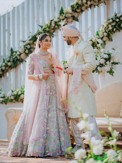 The couple shares a look during their wedding ceremony, with a beautiful floral arch in the background.
