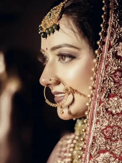 A stunning profile shot of a bride, highlighting her traditional nath and the intricate embroidery on her veil.