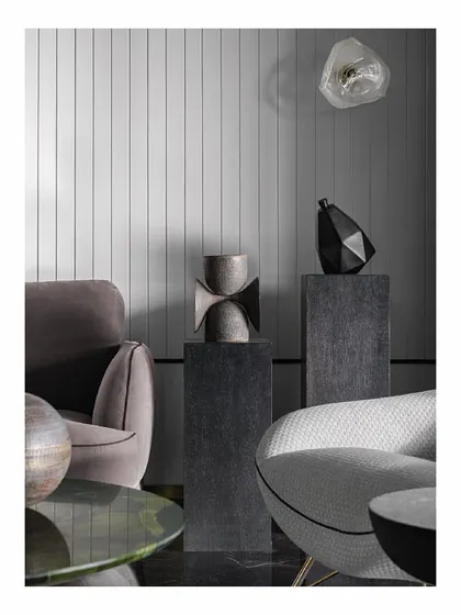 Details from our 'Reflections' project, a sea-facing apartment. We curated sculptural objects and placed them on dark pedestals against a vertically panelled wall. This creates interesting focal points and conversation starters, playing with form and texture in a monochromatic scheme.